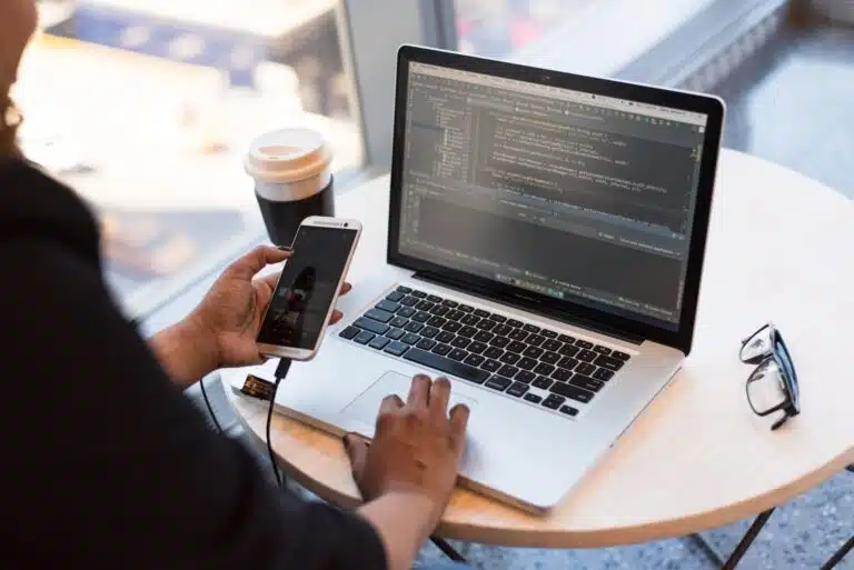 person holding smartphone while using laptop